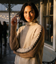 Load image into Gallery viewer, Woman wearing a color block sweater with black contrast stitching down the arms standing outside a home.
