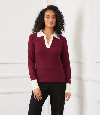 Woman wearing a burgundy sweater with a white collar and black pants against a white background.