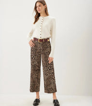 Load image into Gallery viewer, A woman modeling a cream long-sleeve button-front top and cheetah-print cropped wide-leg pants with a brown belt, standing against a plain light background.
