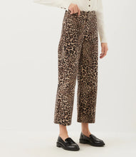 Load image into Gallery viewer, A person wearing cheetah-print cropped pants with a white long-sleeve top and black loafers, shown against a plain light background.
