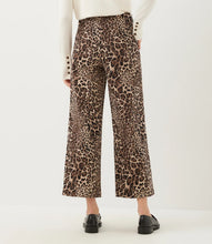 Load image into Gallery viewer, A person shown from the back wearing cheetah-print cropped wide-leg pants, a cream long-sleeve top, and black loafers against a plain light background.
