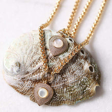 Load image into Gallery viewer, Gold-tone chain necklace with two teardrop-shaped pendants featuring milky white moonstone centers, surrounded by cubic zirconia, displayed on a textured abalone shell.
