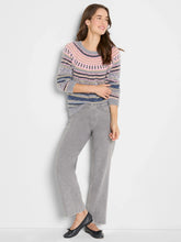 Load image into Gallery viewer, Woman wearing a pink and grey multi fairisle sweater, grey pants and black flats against a white wall.
