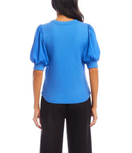 Load image into Gallery viewer, Woman wearing a blue blouse with puffed sleeves and black pants on a white background.
