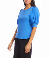 Load image into Gallery viewer, Woman wearing a blue blouse with puffed sleeves and black pants on a white background.

