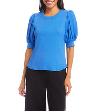 Load image into Gallery viewer, Woman wearing a blue blouse with puffed sleeves and black pants on a white background.

