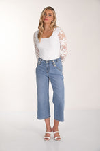 Load image into Gallery viewer, Woman wearing a white lace top, blue jeans with rhinestone buttons and white sandals on a white background.
