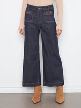 Load image into Gallery viewer, A model is shown from the waist down wearing dark wash wide-leg cropped jeans, a beige ribbed long-sleeve top, and tan suede ankle boots against a white wall.
