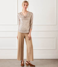 Load image into Gallery viewer, Woman wearing a sequined cardigan, beige pants and brown suede heels against a white wall.
