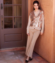 Load image into Gallery viewer, Woman wearing a sequined cardigan. beige pants and black shoes standing against a peach-colored wall.
