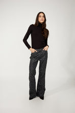 Load image into Gallery viewer, Model wearing black and silver abstract patterned pants, black turtleneck and black heels against a white background.
