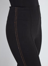 Load image into Gallery viewer, Close-up of black pant with bronze rhinestone embellishments against a gray background.
