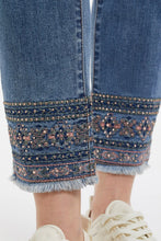 Load image into Gallery viewer, Our Dakota jean blends a classic style with modern flair. The 10 1/4&quot; mid-rise, slim silhouette, 28&quot; inseam, button and fly closure, and functional five pockets make this fabulous jean comfortable and practical. A stunning embroidered hem adds an upscale touch to the classic denim.   Color - Dark vintage blue; rose pink, sage, blue embroidery with gold beading. Embroidered hem. Fly and button closure. Slim leg with 28&quot; inseam. Functional five pockets. Soft stretch denim.

