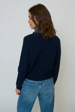 Load image into Gallery viewer, Woman wearing a navy sweater with a denim collar and blue jeans against a plain background.
