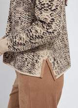 Load image into Gallery viewer, Close up of model wearing a lux camel colored snake jacquard patterned sweater and brown pants against a white background.

