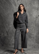 Load image into Gallery viewer, Woman wearing a dark blazer, gray shirt, plaid wide-leg pants and black sandals against a textured gray background.

