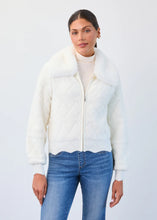 Load image into Gallery viewer, Woman wearing a cream jacket and blue jeans against a white background.

