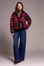 Load image into Gallery viewer, Woman wearing a colorful patterned cardigan over a green turtleneck, blue jeans and burgundy boots against a plain background.
