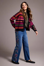 Load image into Gallery viewer, Woman wearing a colorful patterned cardigan over a green turtleneck, blue jeans with embroidery and black Mary Janes against a plain background.
