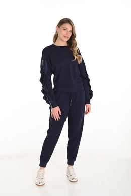 Woman wearing a navy blue outfit and white sneakers against a white background.