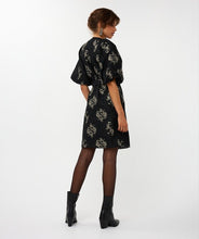 Load image into Gallery viewer, Woman wearing a black and silver floral puff sleeve jacquard dress and black boots against a white background.
