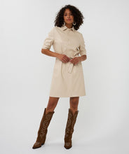 Load image into Gallery viewer, Woman wearing a light sand faux leather dress and brown cowboy boots against a white background.
