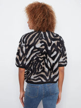 Load image into Gallery viewer, A model shown from the back wearing a fuzzy short-sleeve knit top with a black and beige zebra-like pattern, paired with blue jeans, against a plain white background.

