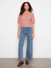 Load image into Gallery viewer, A woman stands against a plain white wall wearing a dusty rose short-sleeve sweater top, blue wide-leg jeans, and brown leather loafers.
