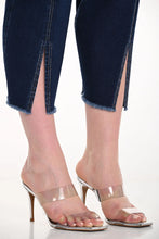 Load image into Gallery viewer, Close up of blue jeans with a slight crop and clear high-heeled sandals on a white background.
