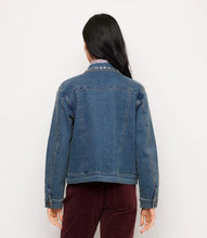 Load image into Gallery viewer, A woman viewed from the back wearing a blue denim jacket with decorative embroidery on the collar, paired with burgundy pants, against a plain white background.
