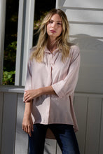 Load image into Gallery viewer, Woman wearing a light pink sequin shirt and dark jeans standing outdoors.

