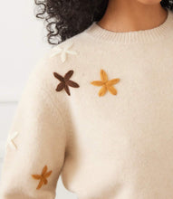 Load image into Gallery viewer, Close-up of model wearing a cream sweater with embroidered flowers against a light background.
