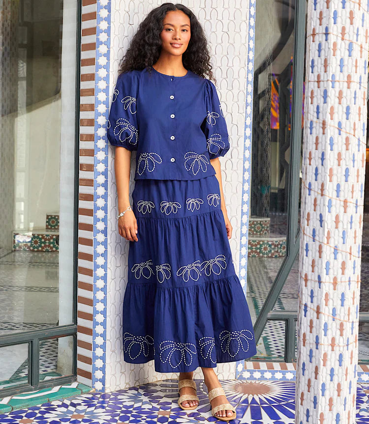 Flowing and feminine, the Karen Kane Embroidered Tiered Midi Skirt is a must-have for effortless style. Designed with three cascading tiers, each adorned with intricate white embroidery, this skirt adds a touch of texture and contrast to your look.