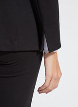 Load image into Gallery viewer, Close up of the split sleeve on the black blazer with a white shirt underneath against a white background.
