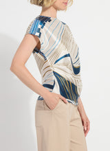 Load image into Gallery viewer, Woman wearing a patterned top and beige pants on a white background.
