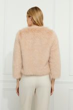 Load image into Gallery viewer, Woman wearing a blush faux fur jacket and vanilla pants against a white wall.
