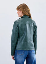 Load image into Gallery viewer, Woman wearing a green leather jacket and blue jeans against a light gray background.
