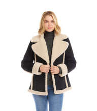 Load image into Gallery viewer, Woman wearing a black coat with cream shearling trim, black turtleneck and blue jeans against a white background.
