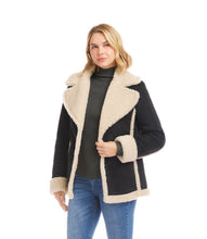 Load image into Gallery viewer, Woman wearing a black coat with cream shearling trim, black turtleneck and blue jeans against a white background.
