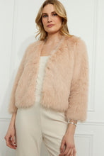 Load image into Gallery viewer, Woman wearing a blush faux fur jacket with pearl embellishments, a vanilla top and vanilla pants against a white wall.
