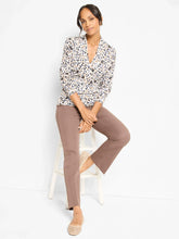 Load image into Gallery viewer, Woman sitting on a white barstool wearing a cheetah print V-neck sweater, taupe pants and off-white flats against a white backdrop.
