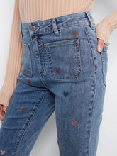 Load image into Gallery viewer, Blue jeans with heart patterns and pockets on a plain background.
