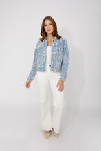 Load image into Gallery viewer, Woman wearing a blue and multi-color embroidered floral patterned jacket, white jeans and beige heels against a white background.
