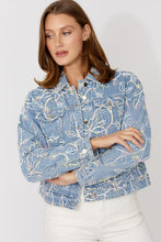 Load image into Gallery viewer, Woman wearing a blue and multi-color embroidered floral patterned jacket and white jeans against a white background.
