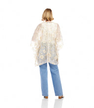 Load image into Gallery viewer, Woman wearing a floral gold and off-white kimono over a white top and blue jeans and white sandals standing against a white wall.
