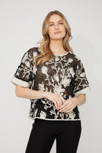 Load image into Gallery viewer, Woman wearing a sheer black embroidered floral patterned sequin short sleeve top and black pants against a white background.
