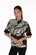 Load image into Gallery viewer, A woman wearing a short-sleeve mock-neck knit sweater with a brown and off-white abstract floral pattern, paired with black pants, against a plain white background.
