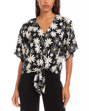 Load image into Gallery viewer, Woman wearing a black short sleeve tie top with white daisies and black pants on a white background.
