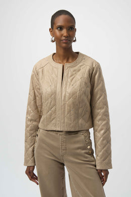 Woman wearing a warm taupe quilted jacket with silver embellishments and warm taupe jeans against a white background.