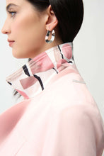 Load image into Gallery viewer, Close-up of model wearing light pink jacket with raised collar with abstract print and silver earrings against a white background.
